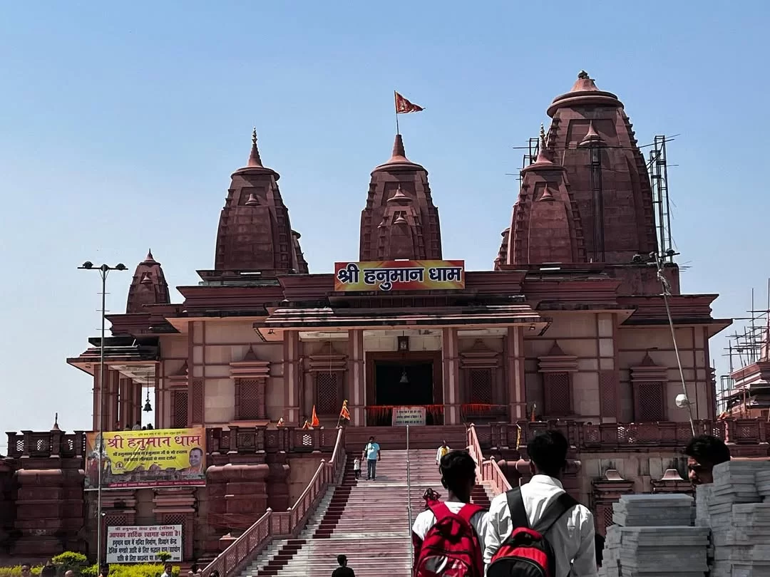 Hanuman Dham Temple at Jim Corbett Uttarakhand during sunny day, featuring red sandstone shikharas and temple signboard, perfect spiritual experience Uttarakhand tour package.