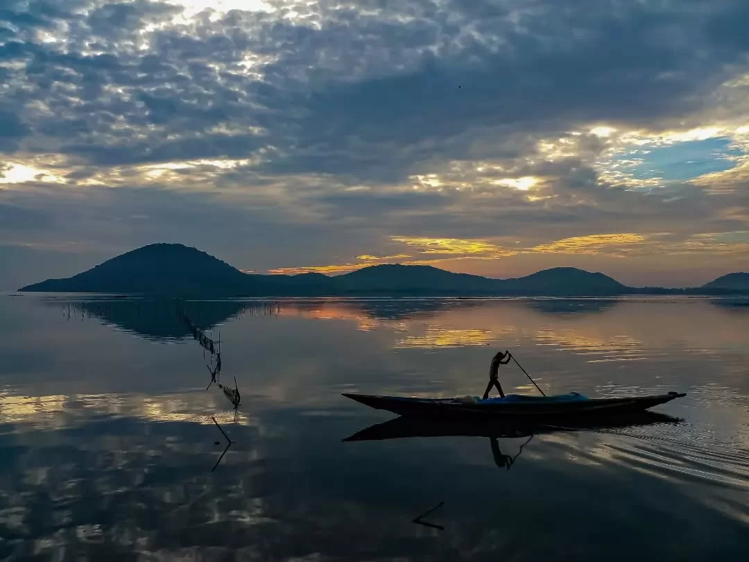 Chilika Lake Odisha silhouette fisherman boat sunset golden hour hills reflection tranquil waters, perfect Puri birdwatching boat safari tour package.