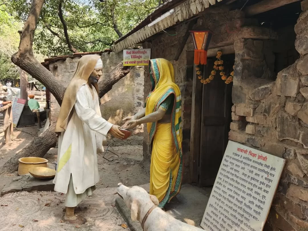 Sai Baba giving nine coins to Laxmibai Shinde statue at Sai Heritage Village near Naini Lake Nainital, depicting final leela moment from Sai Satcharitra Chapter 42 with Marathi signboard, perfect cultural heritage experience Uttarakhand tour package.