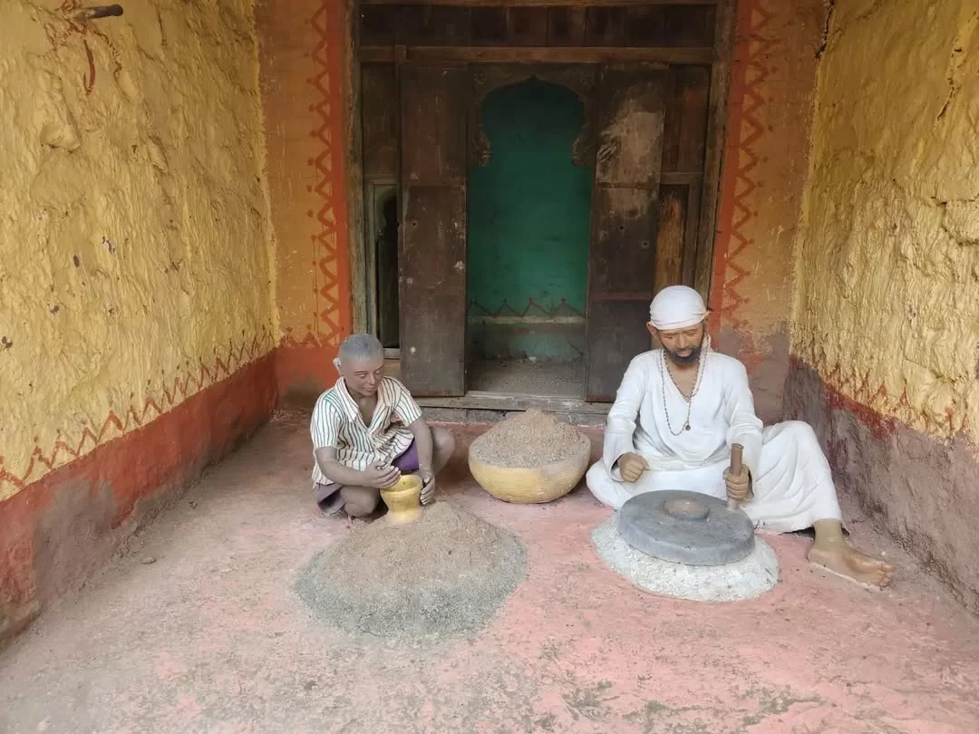 Sai Baba grinding wheat statue with young boy assistant at Sai Heritage Village near Naini Lake Nainital, depicting traditional Dwarkamai scene from Sai Satcharitra, perfect cultural heritage experience Uttarakhand tour package.