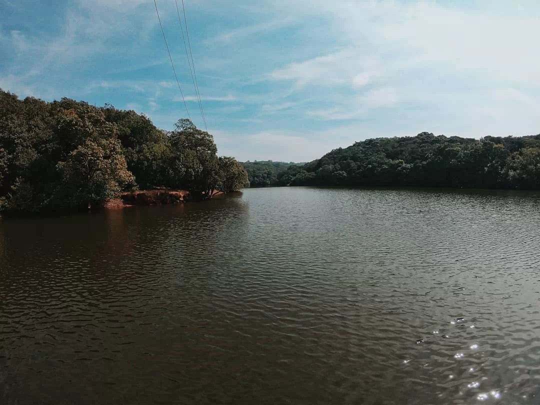 Charlotte Lake at Matheran during partly cloudy skies, featuring lush forested banks and calm water ripples, perfect romantic experience Maharashtra tour package.