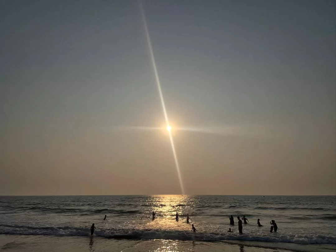 Sun rays piercing over Benaulim Beach Goa during golden hour sunset, featuring kids playing beach waves sparkling sea, perfect South Goa tour package.