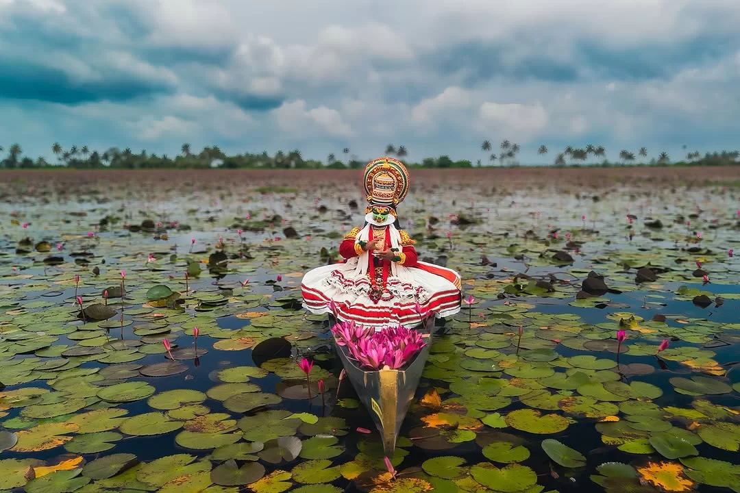 Kerala Alleppey backwaters Kathakali dancer boat lotus flower filled lily pads pink lotuses coconut palm trees cloudy sky aerial drone shot, cultural heritage houseboat tour package