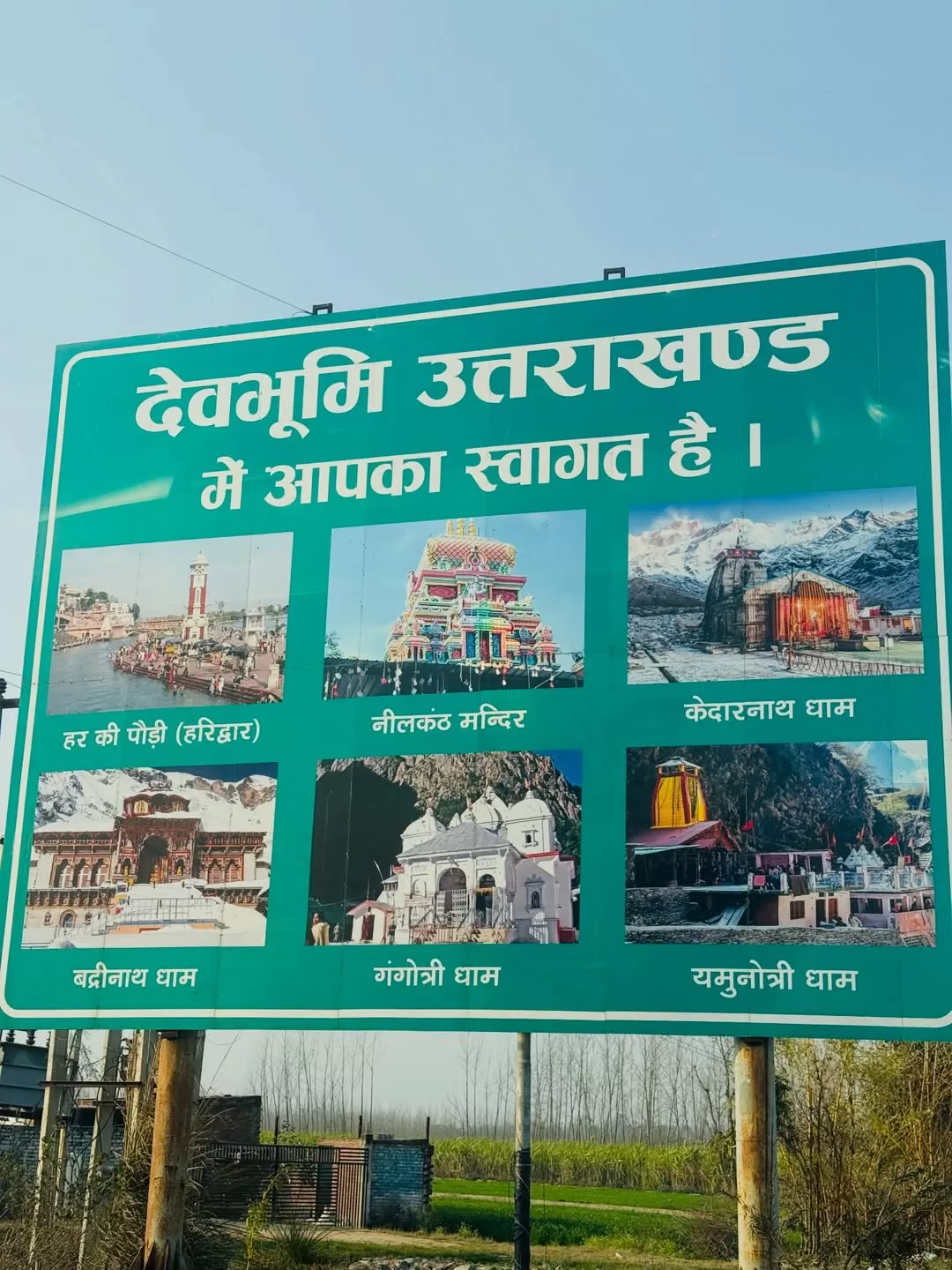Welcome signboard reading Devbhoomi Uttarakhand featuring images of Char Dham temples including Kedarnath Badrinath Gangotri and Yamunotri promoting spiritual Uttarakhand tour packages