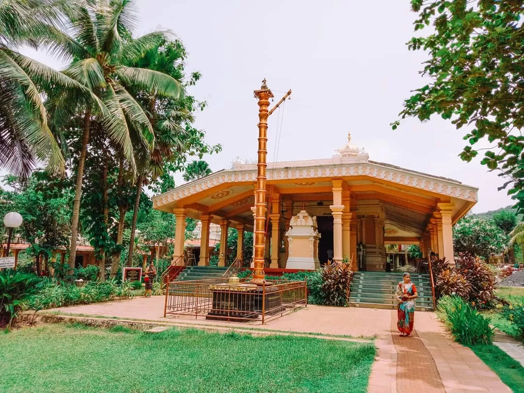 Vibrant Tirupati Balaji Temple North Goa with tall flagpole and devotees, surrounded by palm trees and lush gardens, perfect divine blessings spot with Goa tour package. 
