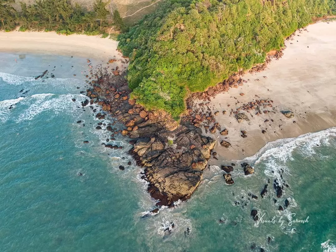 Aerial Galgibaga Beach Goa pristine golden sands rocky outcrops, lush green cliffs Arabian Sea waves palm fringes, perfect South Goa turtle nesting eco beach package. 