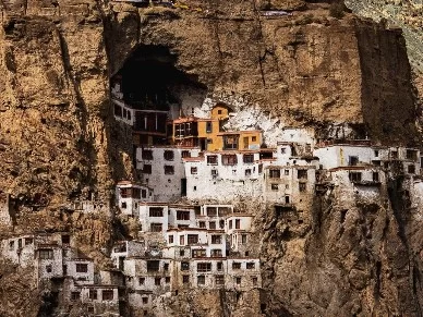Monasteries at Zanskar Valley during golden hour, featuring cliffside white buildings, rocky mountains, perfect adventure experience with Ladakh Zanskar tour package.