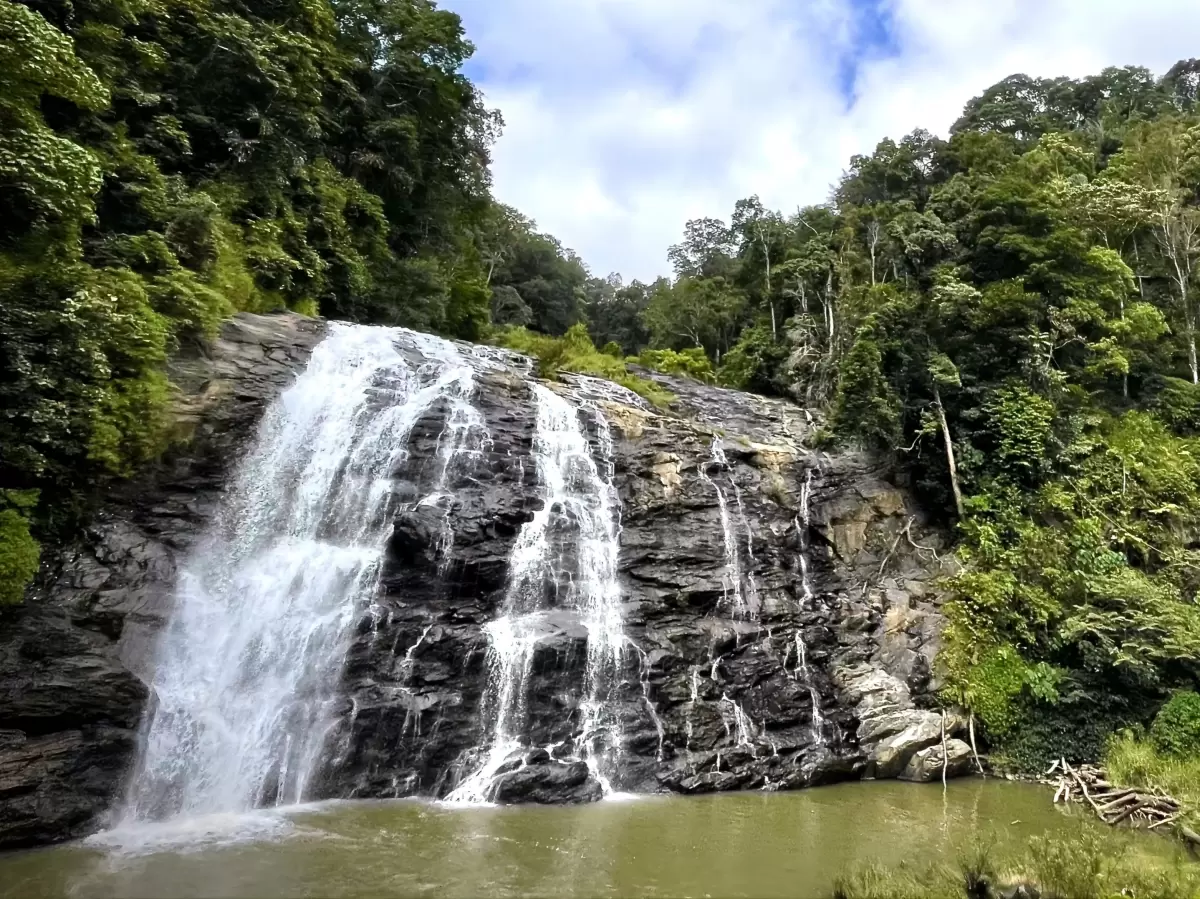 Abbey Waterfall at Madikeri Coorg during partly cloudy day, featuring cascading falls, rainforest and pool, perfect adventure Coorg tour package.