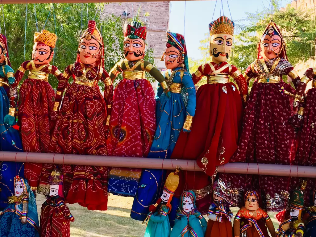 Rajasthani Kathputli puppets collection vibrant traditional folk art dolls in colorful royal attire turbans and lehengas hanging outdoors, iconic Rajasthan handicraft souvenir for cultural heritage to