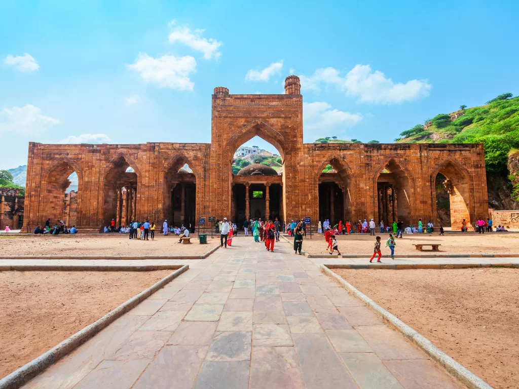 Adhai Din Ka Jhonpra Ajmer red sandstone mosque with grand central arched gateway multiple pillars visitors and Taragarh hill backdrop, historic Indo-Islamic monument in Ajmer Rajasthan tour packages