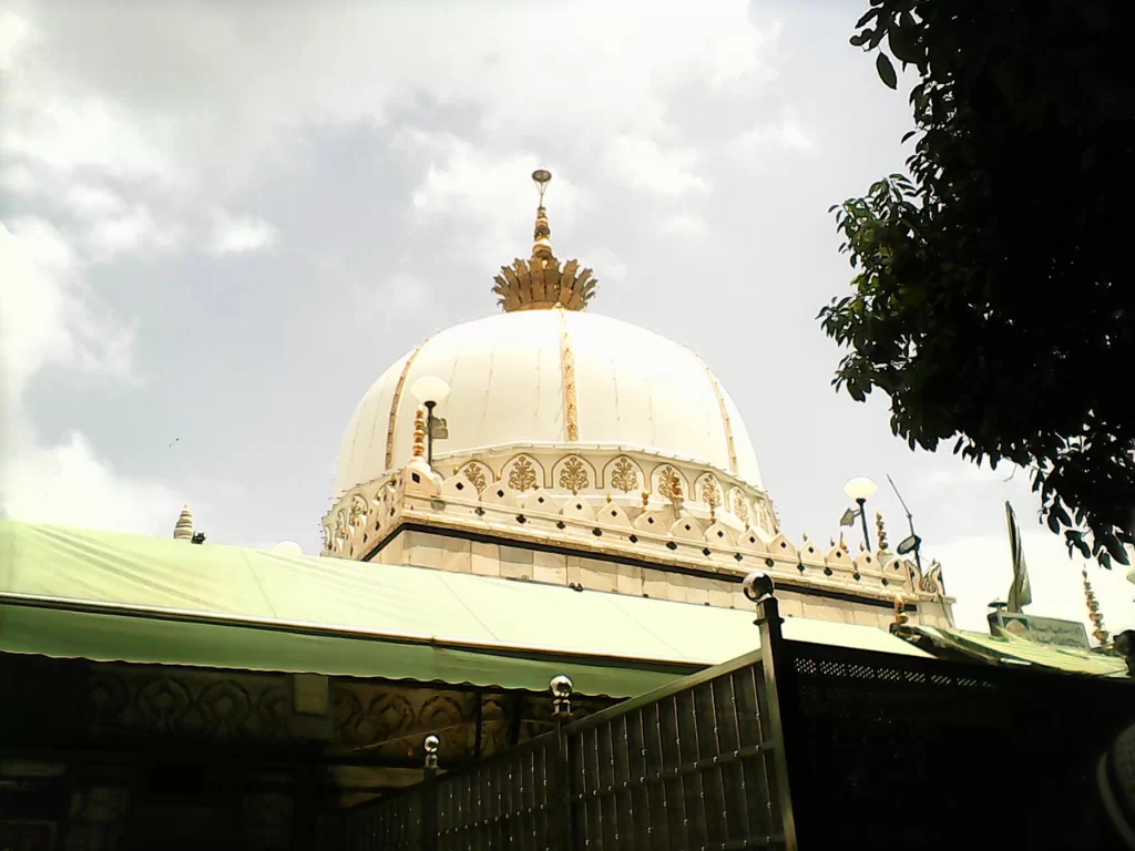 Ajmer Sharif Dargah white buildings green domes minarets arches railings markets tents Khwaja Moinuddin Chishti Sufi shrine complex Rajasthan India historic Islamic architecture.