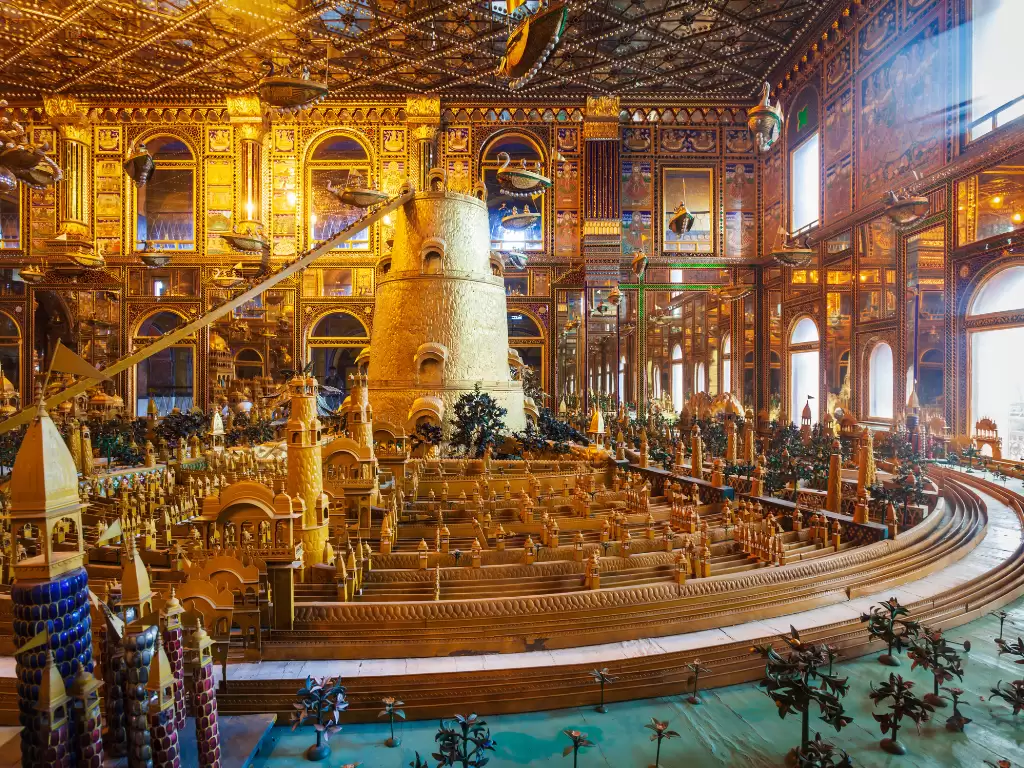 Golden miniature model at Ajmer Jain Temple Rajasthan in bright lighting, featuring ornate tower arches and intricate wood carvings, perfect spiritual Rajasthan tour package.