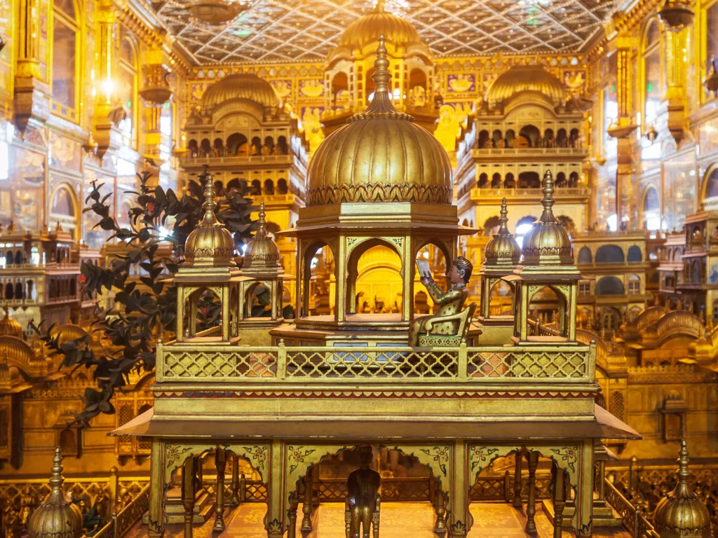 Golden miniature shrine model at Ajmer Soniji ri Jain Temple Rajasthan in illuminated hall, featuring dome pavilions and carved details, perfect spiritual Rajasthan tour package. ​