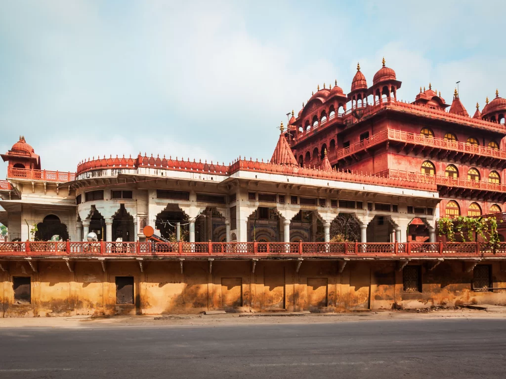 Red sandstone temple facade at Ajmer Soniji ri Jain Temple Rajasthan in partly cloudy skies, featuring domes pillars and intricate carvings, perfect spiritual Rajasthan tour package.