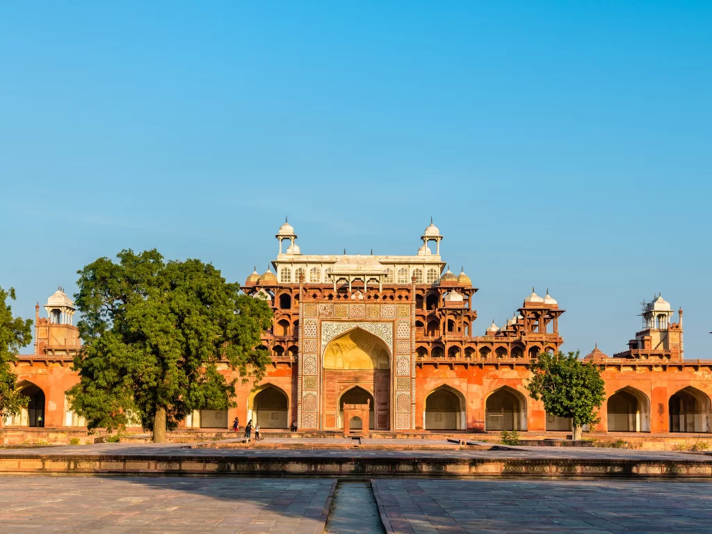 Akbar's Tomb Agra Uttar Pradesh grand sandstone gateway intricate jali work white marble inlays trees courtyard blue sky Mughal architecture UNESCO heritage site, perfect Golden Triangle heritage tour package.