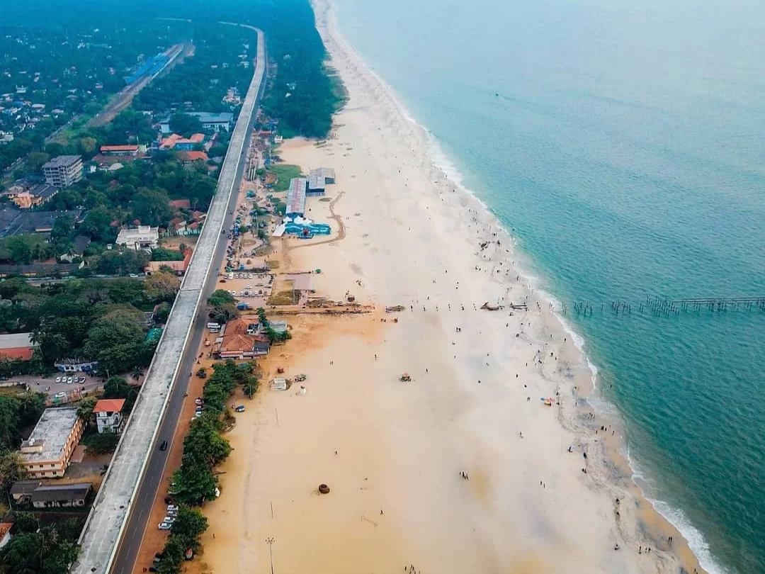 Alappuzha Beach, Kerala India scenic Arabian Sea coastline with golden sand, pier ruins and coastal highway aerial view.