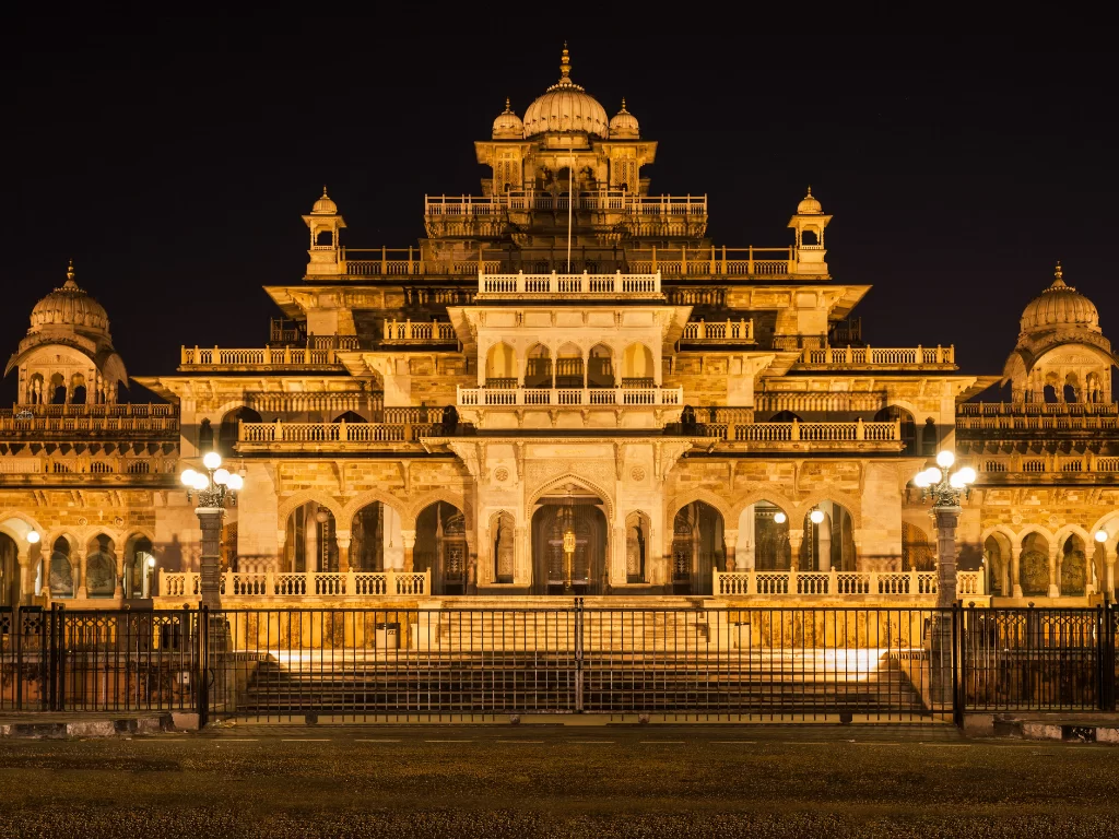 Albert Hall Museum in Jaipur at night illuminated in golden lights showcasing Indo-Saracenic architecture with domes, arches and railings, perfect Rajasthan tour package.