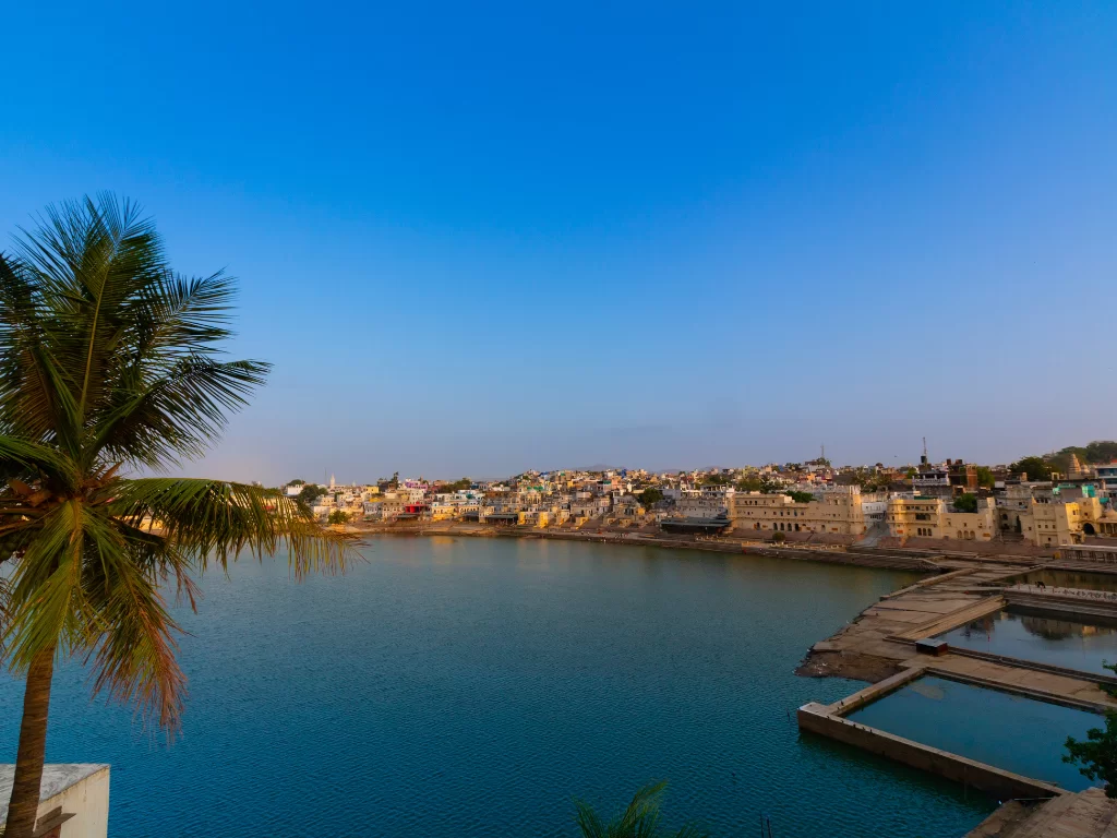 Ana Sagar Lake Ajmer Rajasthan panoramic view at golden hour featuring colorful waterfront buildings palm trees ghats and vibrant blue waters, perfect heritage Rajasthan tour package attraction