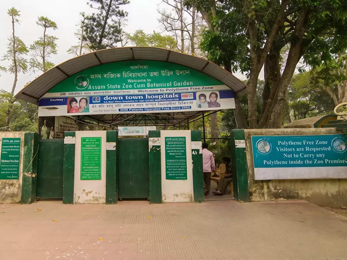 Main entrance gate at Assam State Zoo cum Botanical Garden Guwahati during cloudy day, featuring welcome sign trees bamboo fence, perfect family experience Assam tour package.