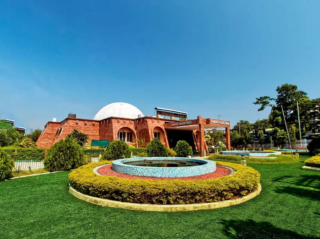 Assam State Zoo cum Botanical Garden entrance at Guwahati during sunny day, featuring dome building fountain greenery trees, perfect family experience Assam tour package.
