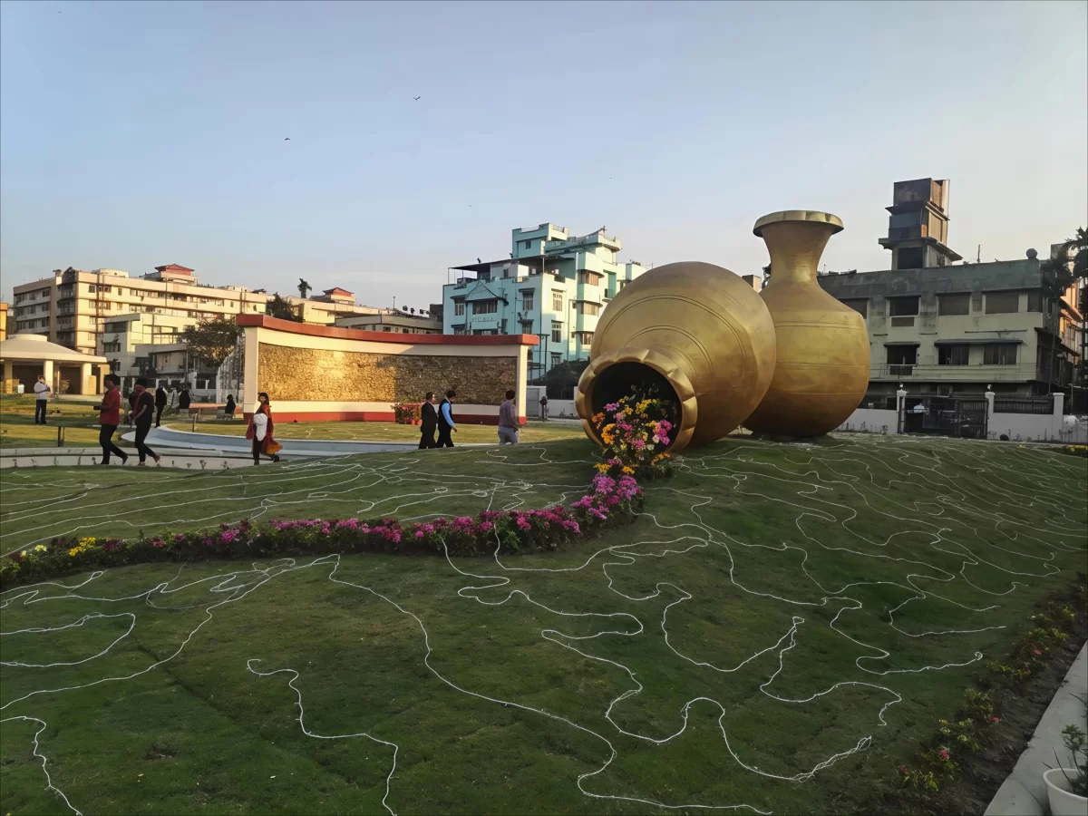Giant golden flower pot sculptures at Atal Udyan Adabari Park Guwahati during sunset, featuring colorful flowers green lawns, perfect family experience Assam tour package. 