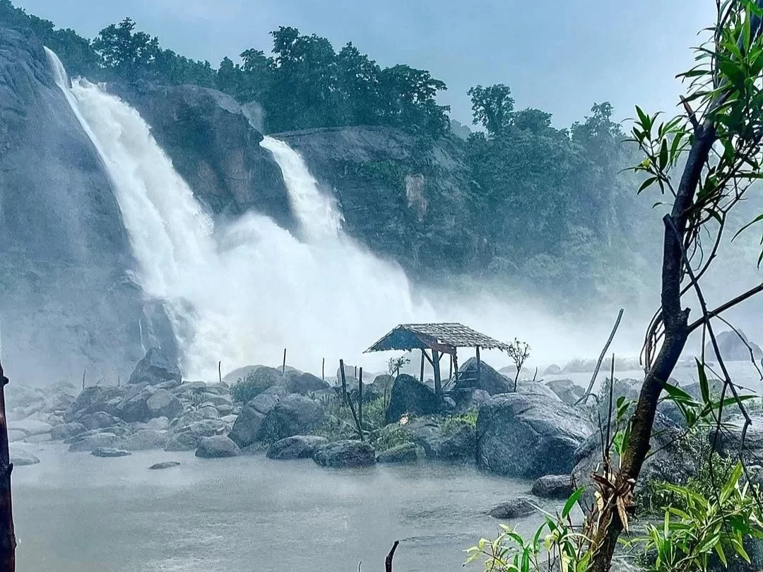Athirapilly Waterfall in Kerala, majestic cascading waterfall amid lush forest and rocky landscape.