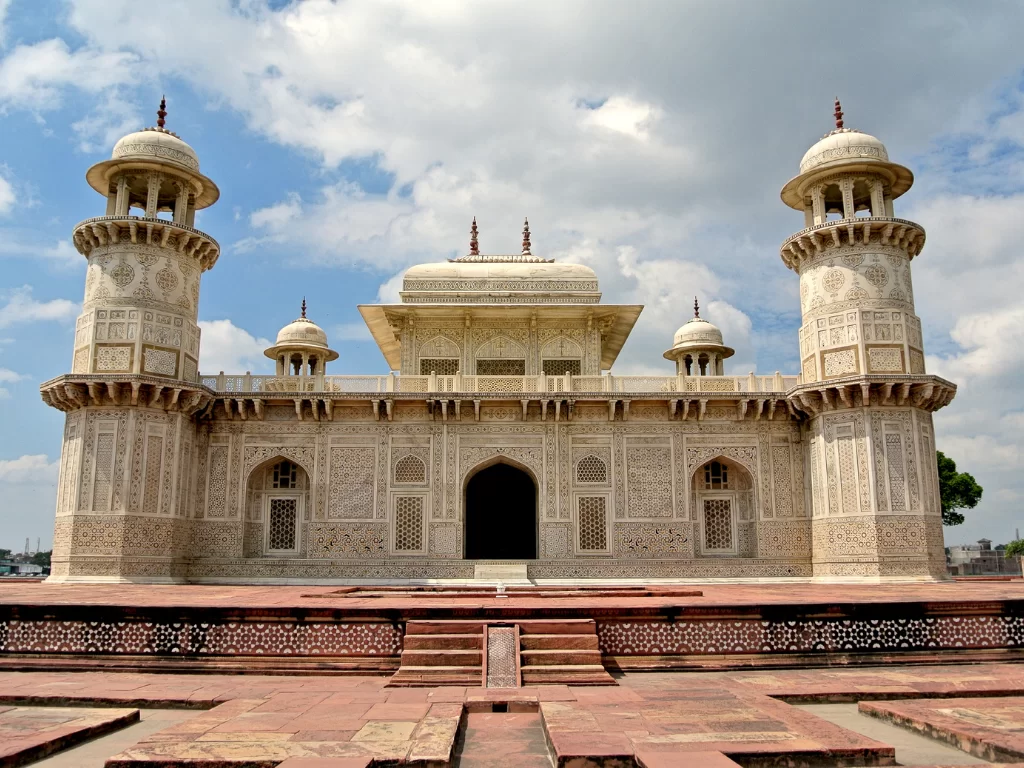 Main tomb at Baby Taj Agra Uttar Pradesh during cloudy skies, featuring white marble minarets, jali screens, domes, red sandstone platform, gardens, perfect Golden Triangle heritage tour package. 