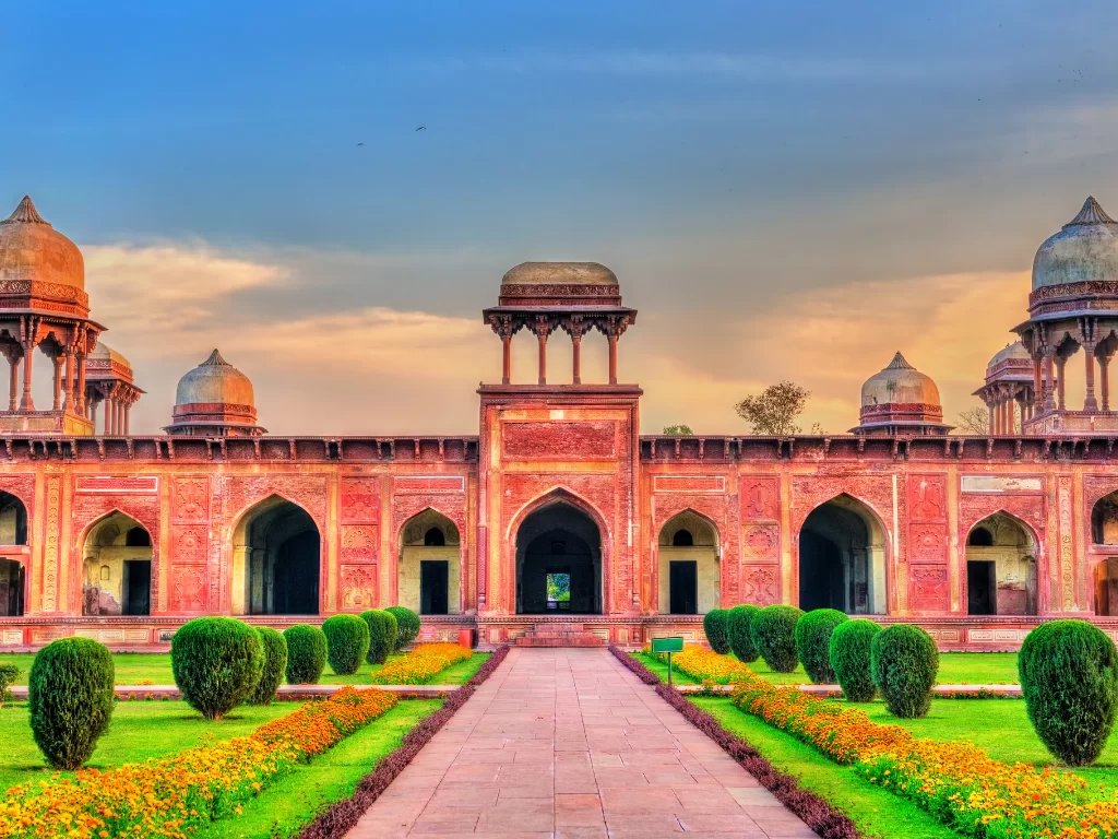 Main pavilion at Baby Taj Agra Uttar Pradesh during sunset, featuring red sandstone arches, domes, lush gardens, hedges, flowers, perfect Golden Triangle heritage tour package.