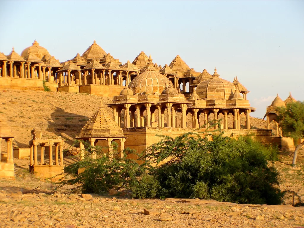 Bada Bagh Jaisalmer panoramic row of golden sandstone chhatris domes atop arid hill with sparse trees, rajasthan tour packages. 