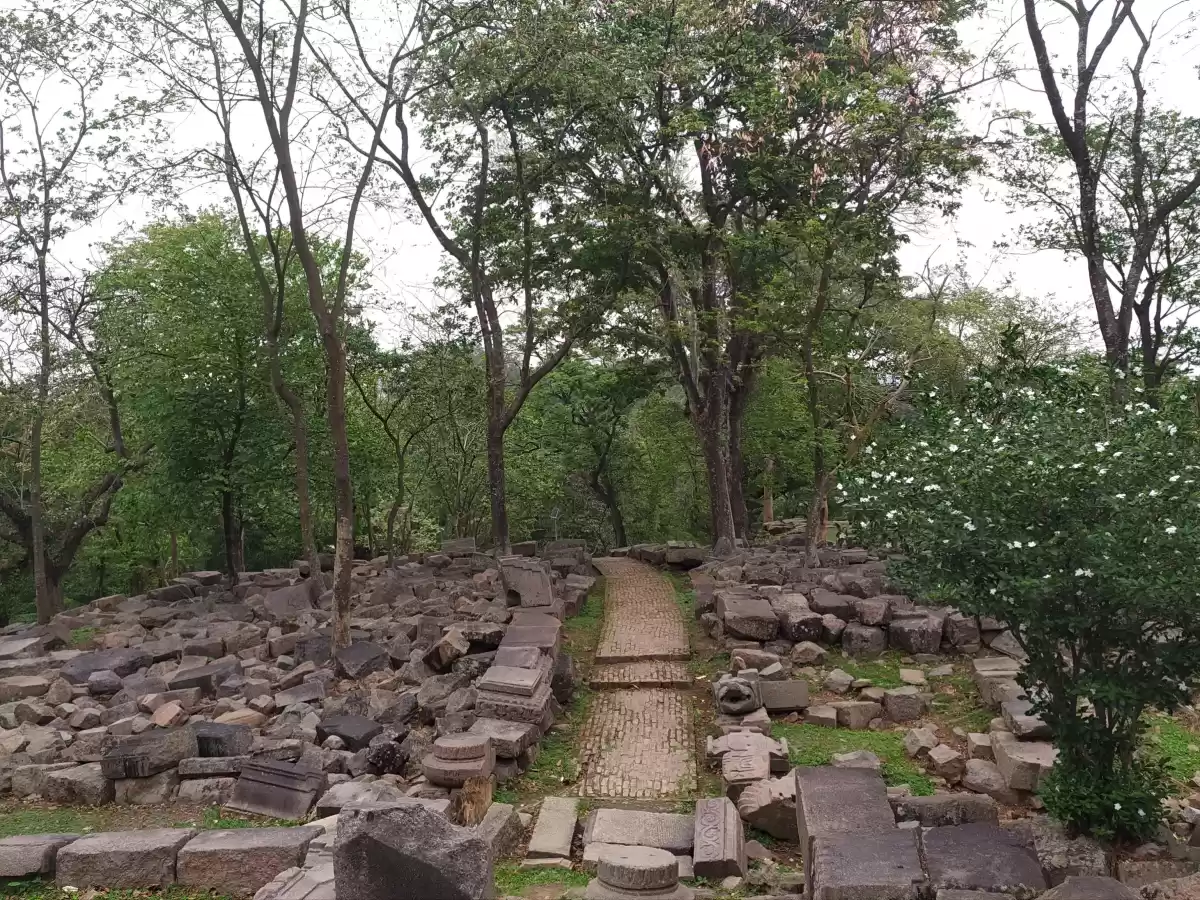 Bamuni Hills Tezpur ancient stone ruins scattered blocks brick pathway trees greenery cloudy sky Chitralekha Udyan park, perfect 9th-10th century archaeological exploration Assam tour packages.