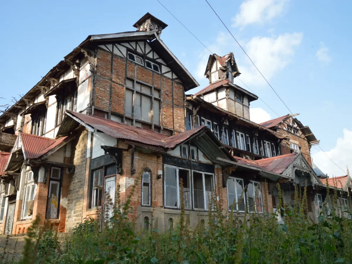 Bantony Castle in Shimla showcasing historic colonial-era architecture with brick walls, wooden beams, and sloped tin roofs surrounded by greenery.