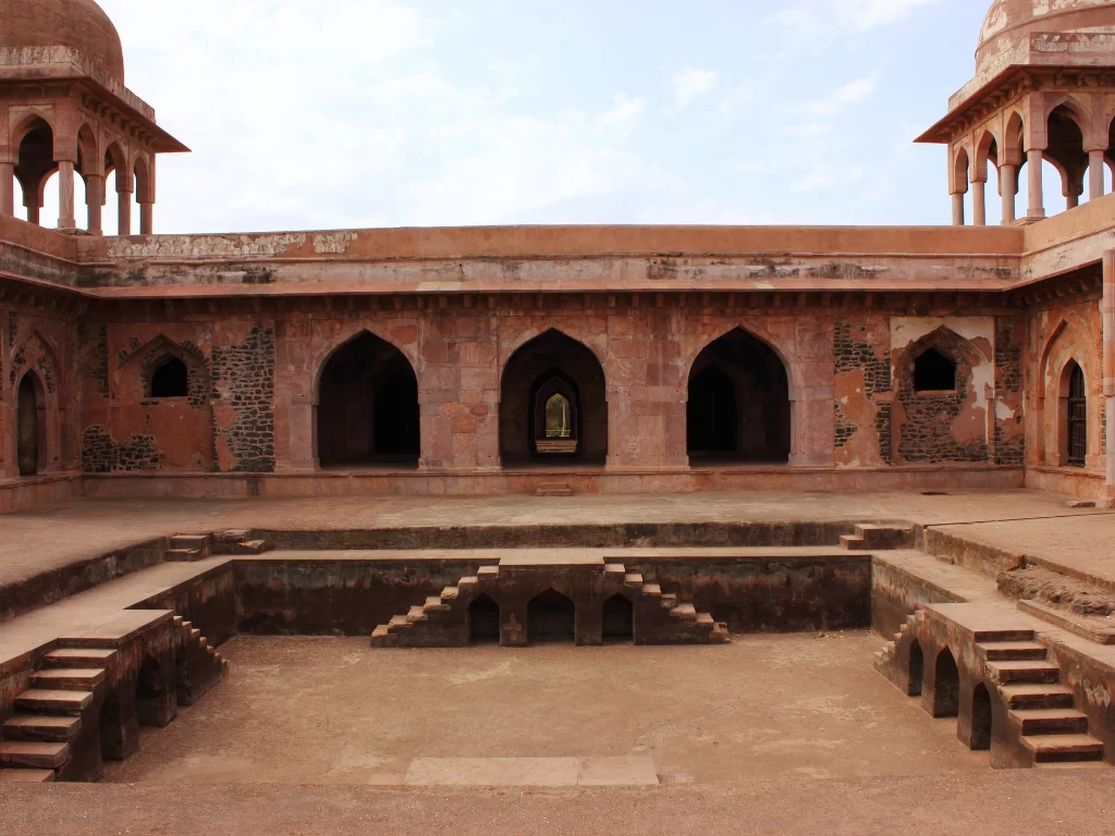 Baz Bahadur Palace courtyard at Gwalior Fort under clear skies, featuring domed pavilions and central stepwell, perfect heritage experience with Madhya Pradesh tour packages.