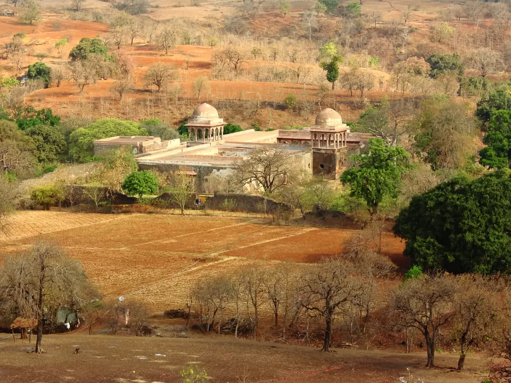 Baz Bahadur Palace at Mandu under golden hour, featuring domed pavilions amid hillside fields, perfect heritage experience with Madhya Pradesh tour packages.