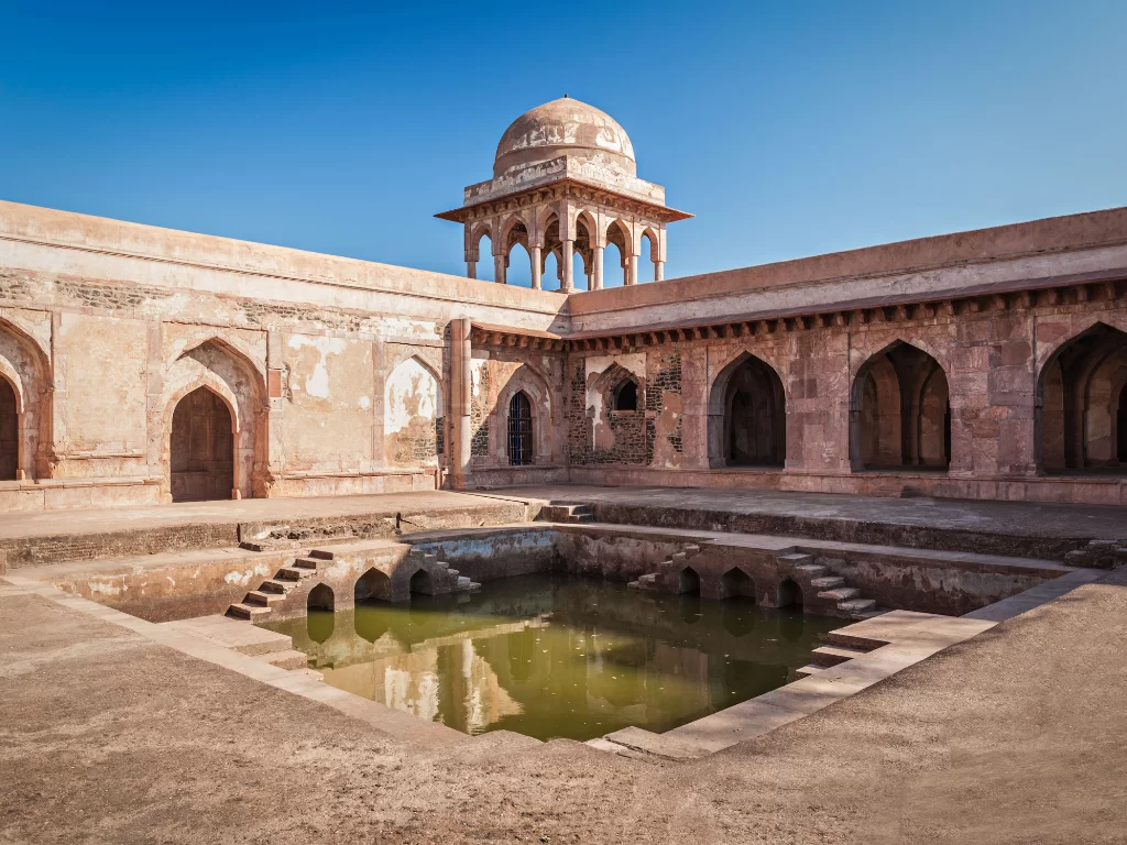 Baz Bahadur Palace at Gwalior Fort under clear skies, featuring domed pavilion and central stepwell, perfect heritage experience with Madhya Pradesh tour packages.