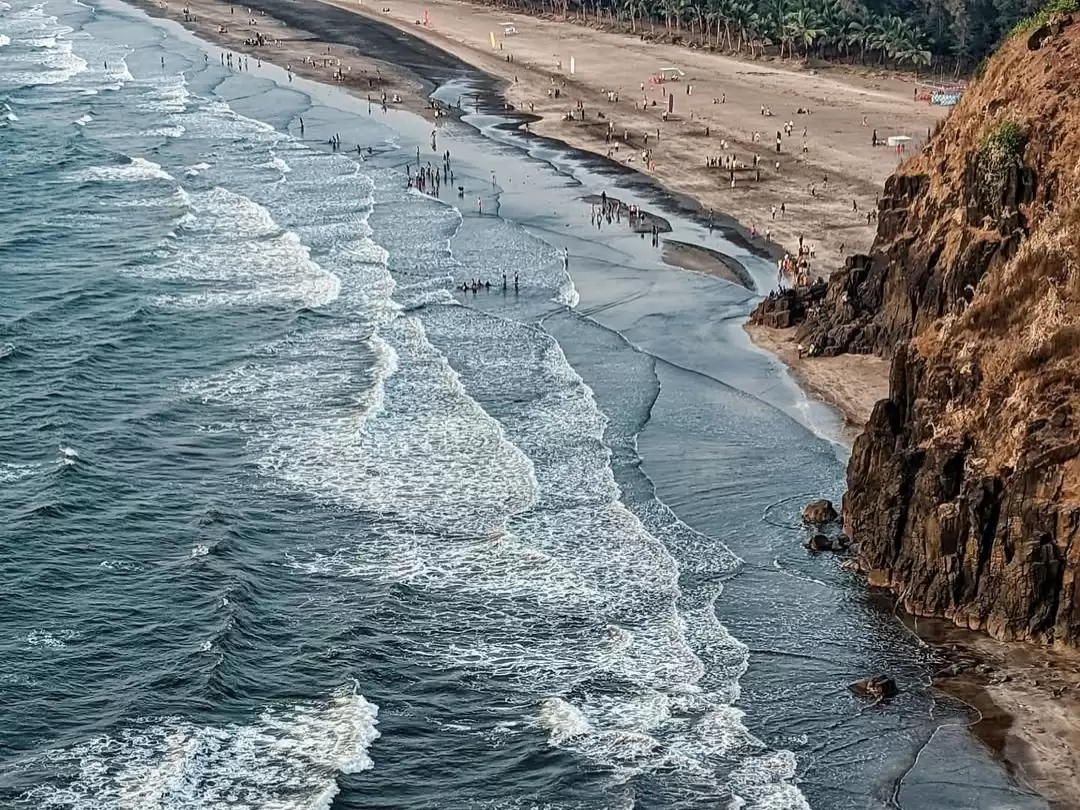 Aerial view of Bhatye Beach in Ratnagiri, Maharashtra, with waves rolling onto the sandy shoreline and rocky cliffs along the coast, a scenic stop featured in Maharashtra tour packages.