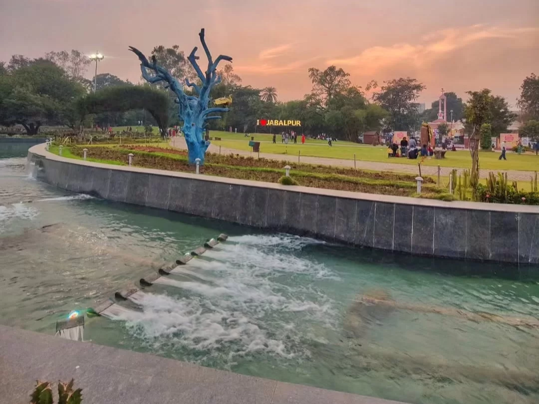  Bhawartal Garden in Indore featuring landscaped lawns, a flowing water channel, and evening visitors under a sunset sky, a popular stop in Madhya Pradesh tour packages