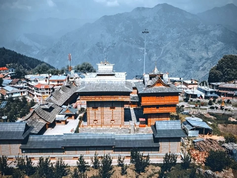 Bhimakali Temple at Sarahan during misty winter, featuring wooden pagoda towers, village houses, Himalayan peaks, perfect spiritual Himachal Pradesh tour package.