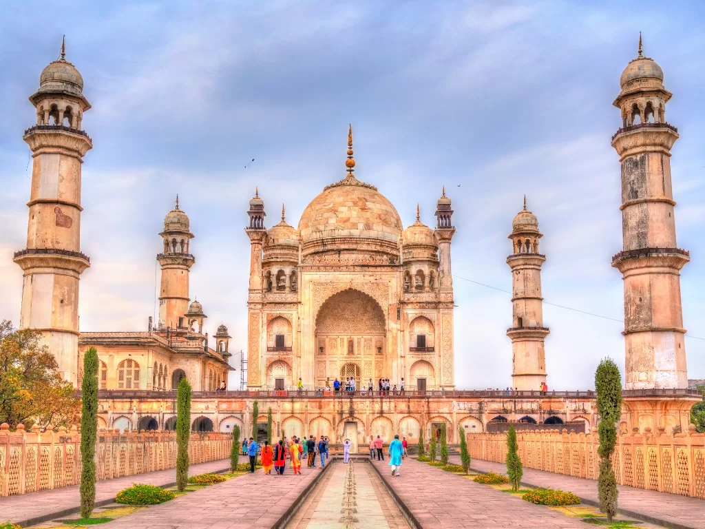 Bibi Ka Maqbara Aurangabad with tourists during partly cloudy day, featuring beige domes minarets gardens pathway visitors, perfect Maharashtra heritage tour package.