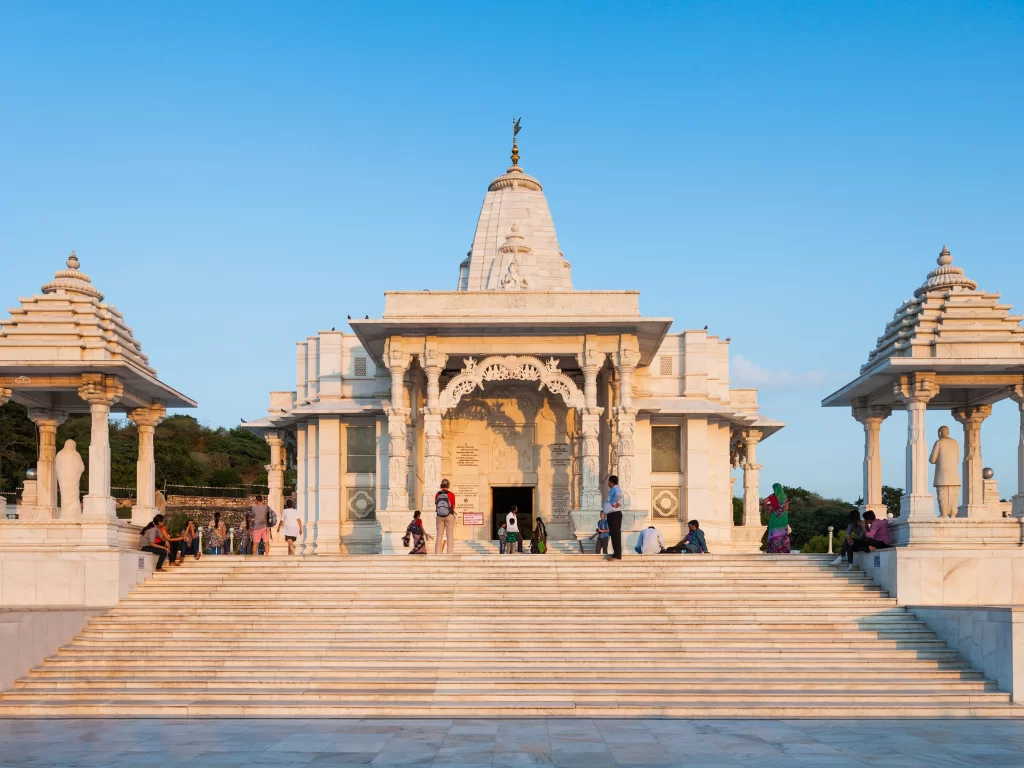 Grand white marble Birla Mandir Laxmi Narayan Temple Jaipur Rajasthan with three domes flanking pavilions wide steps statues under golden sunset blue sky tourists ascending, perfect Rajasthan tour package