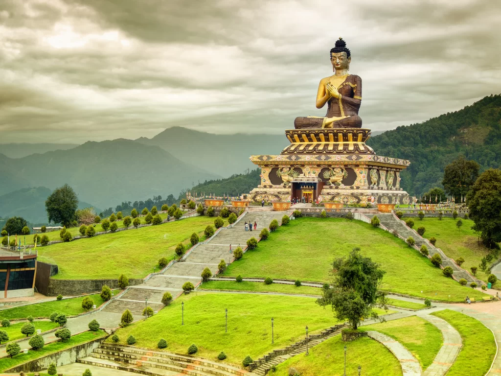 Buddha Park of Ravangla during cloudy daylight, featuring towering Buddha statue, manicured lawns and mountain backdrop, perfect spiritual Sikkim tour package.