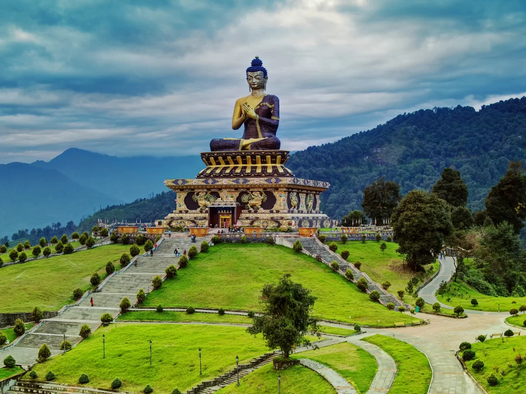 Buddha Park at Ravangla during cloudy daylight, featuring monumental seated Buddha statue, terraced lawns and forested hills, perfect spiritual Sikkim tour package.