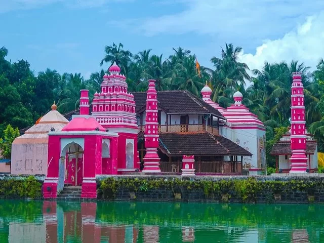 Colorful temple complex by the water in Chaul Village, Maharashtra, surrounded by palm trees and traditional Konkan architecture, a heritage destination included in Maharashtra tour packages.