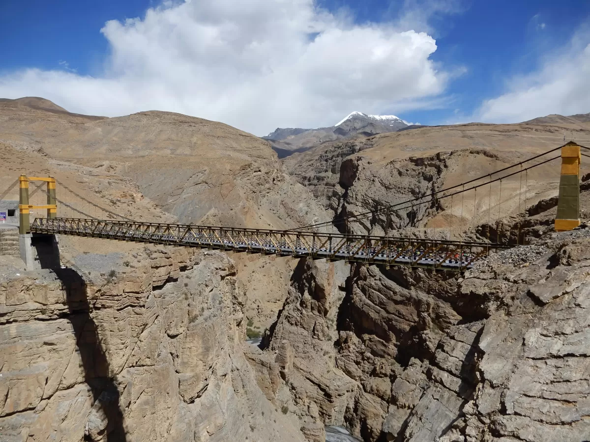 Chicham Bridge near Losar Spiti Valley during partly cloudy skies, featuring Asia's highest suspension bridge spanning deep gorge snow-capped peaks, perfect adventure experience Himachal Pradesh tour package.