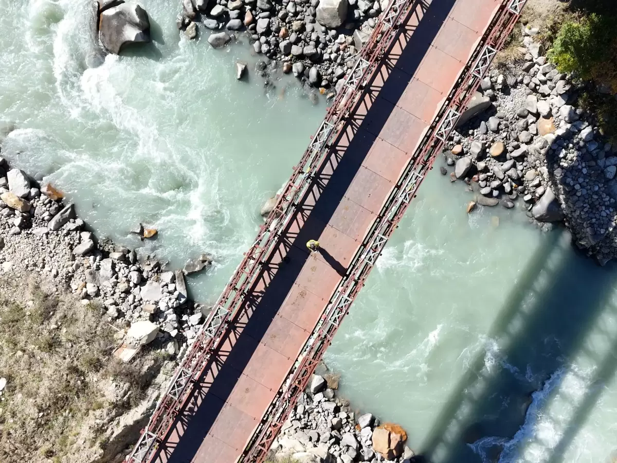 Chitkul Suspension Bridge Baspa River Chitkul Village Kinnaur Himachal Pradesh aerial view turquoise river rapids rocky banks red truss structure, perfect cultural experience Himachal tour package.
