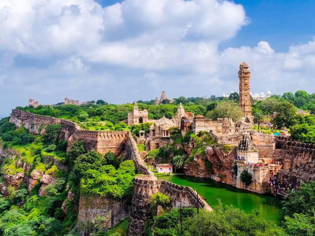 Panoramic ramparts of Chittorgarh Fort in Rajasthan under blue sky, featuring Vijay Stambh, temples and pond, perfect Rajasthan tour package.
