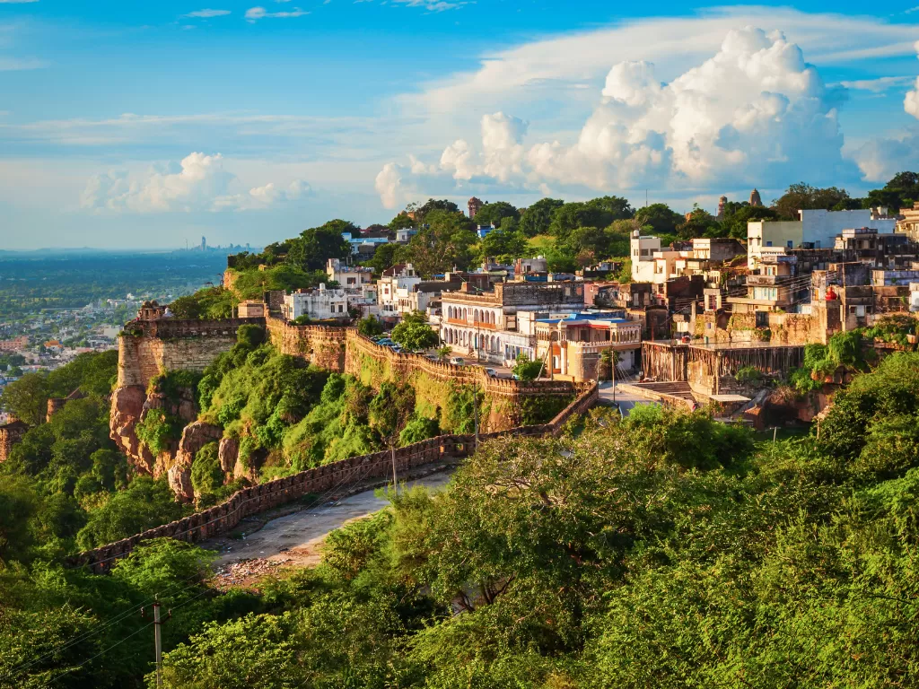 Hilltop view of Chittorgarh Fort in Rajasthan during sunny day, featuring ramparts, cliffs and cityscape, perfect Rajasthan tour package.