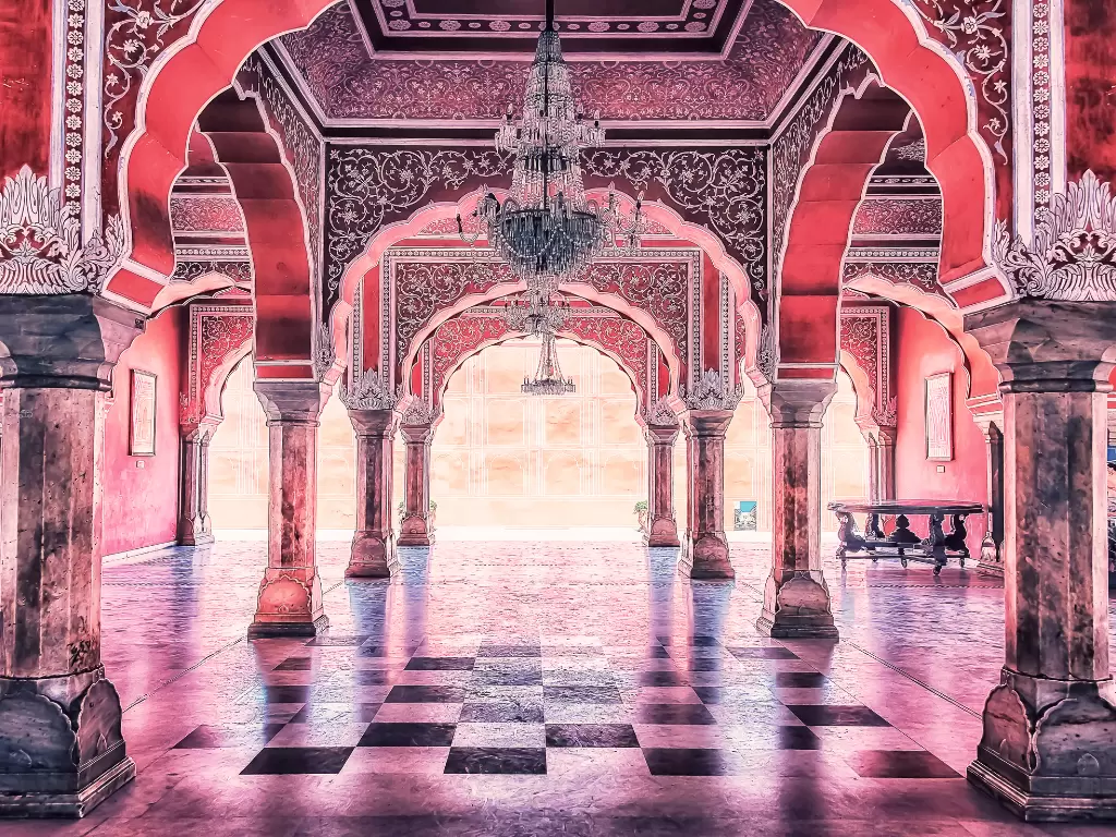 Opulent pink marble Diwan-i-Khas Mubarak Mahal hall inside City Palace Jaipur Rajasthan with ornate red arches hanging chandeliers checkered floor golden sunlight streaming through pillars, perfect Rajasthan tour package.