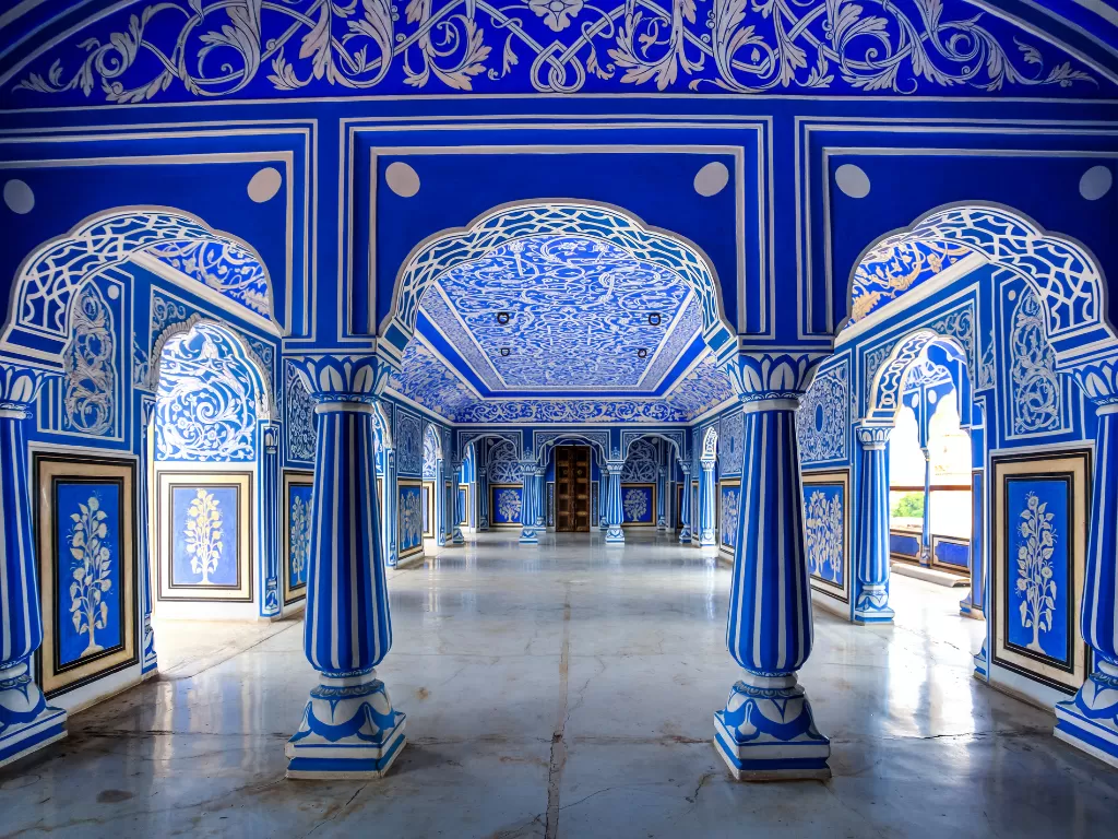 Vibrant blue peacock gate corridor inside City Palace Jaipur Rajasthan with white floral motifs coin circles ornate pillars polished marble floor iconic Rajasthani architecture, perfect Rajasthan tour package
