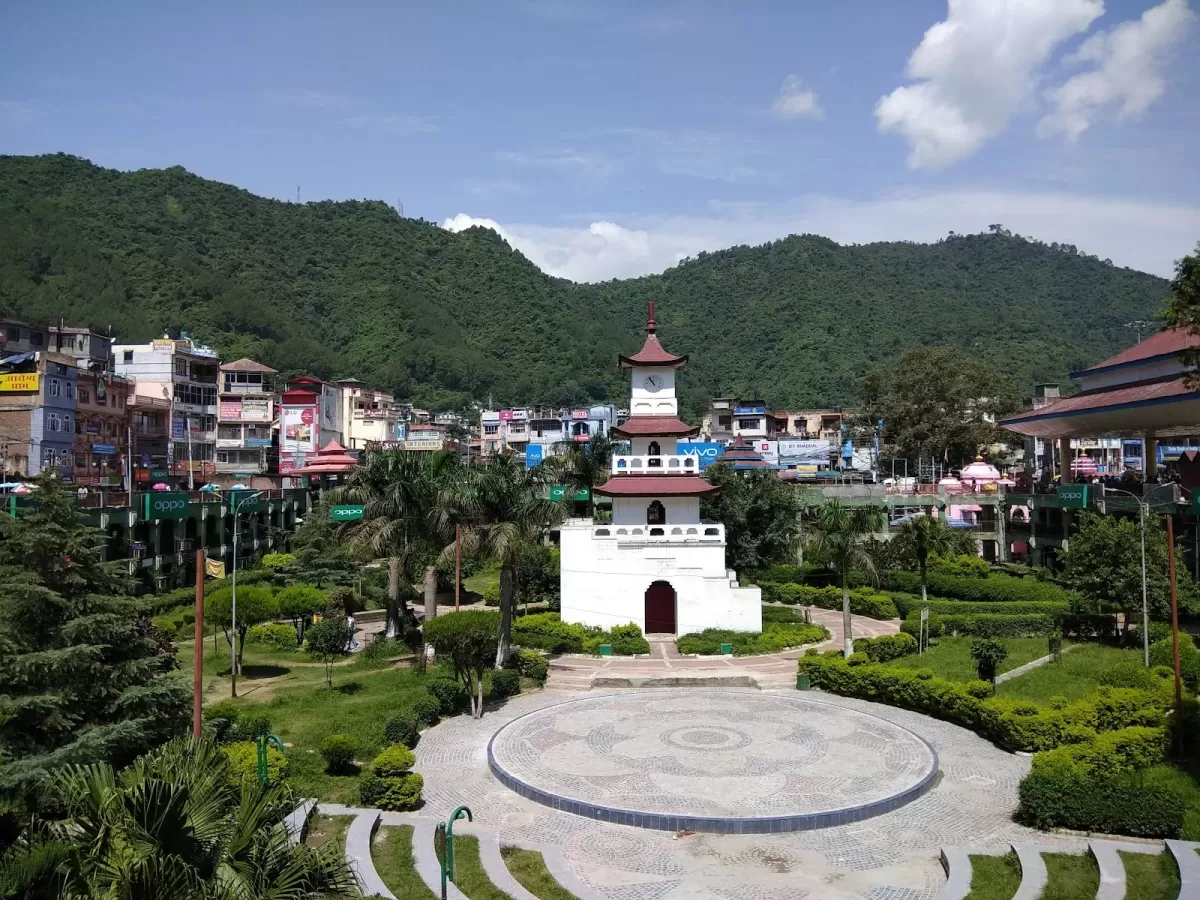 Clock Tower at Mandi Himachal Pradesh during clear skies, featuring white pagoda structure amid green hills and town buildings, perfect heritage experience Himachal Pradesh tour package.
