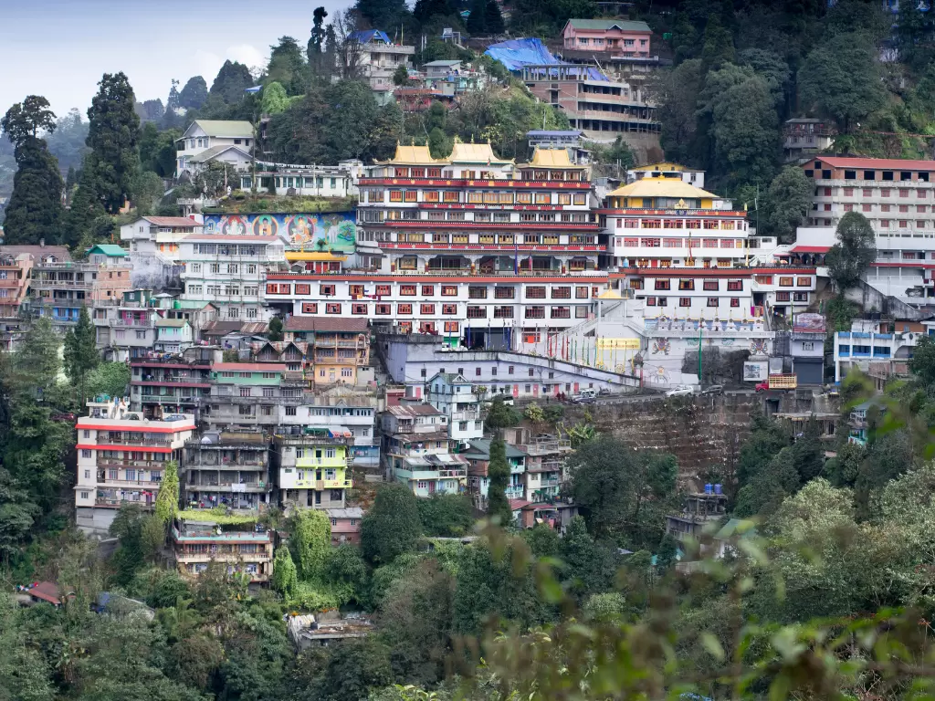 Dali Monastery in Darjeeling on hillside during cloudy daytime, featuring layered buildings and forested slopes, perfect spiritual Darjeeling tour package